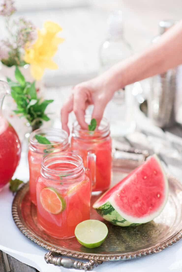 hand placing mint garnish into a watermelon Mexican mule