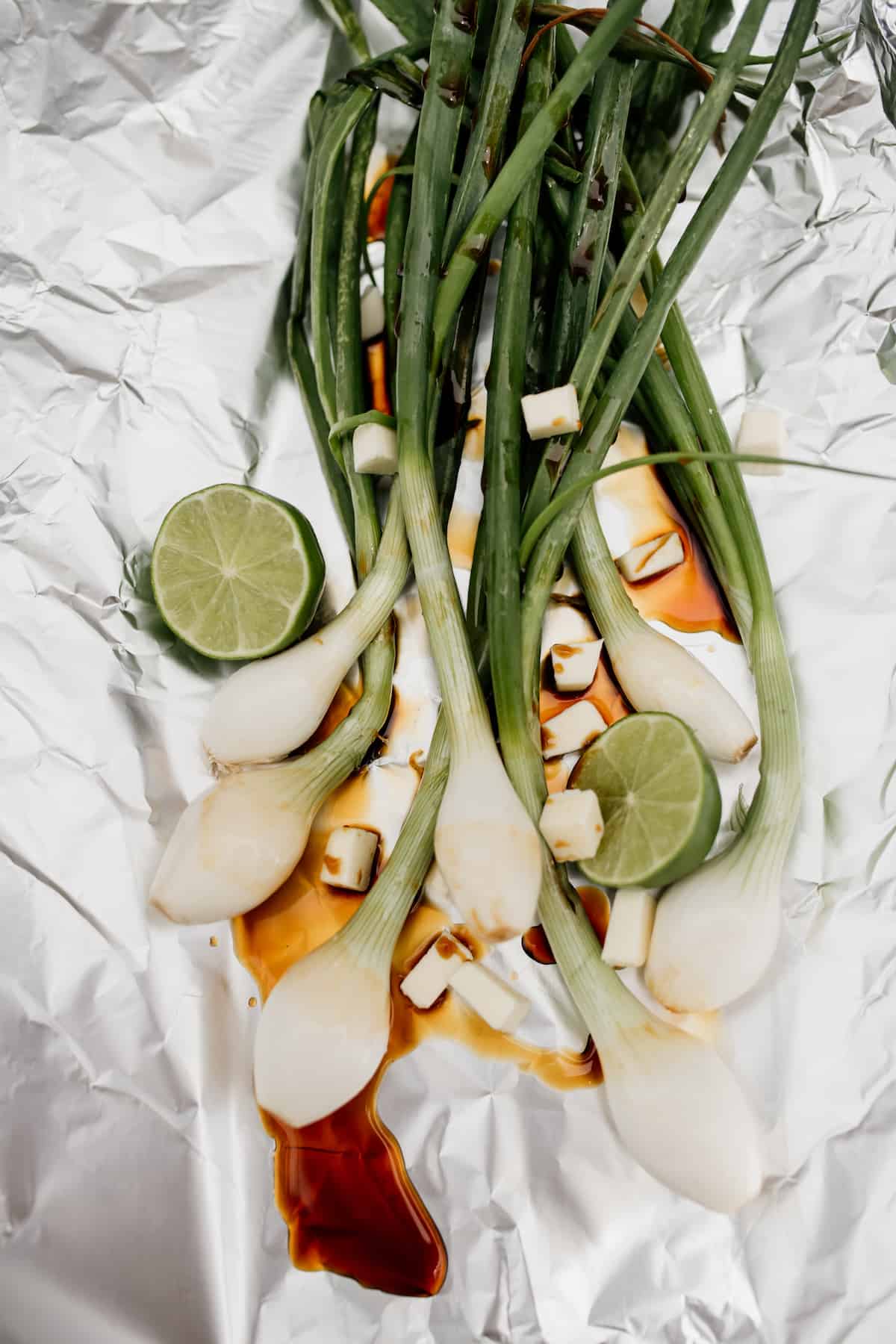 spring onions on a piece of foil with soy sauce and lime for grilling