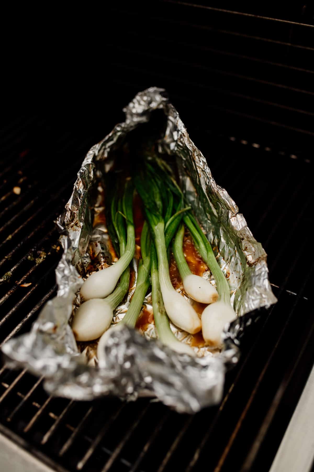 foil packet of green spring onions on the grill for making cebollitas asadas