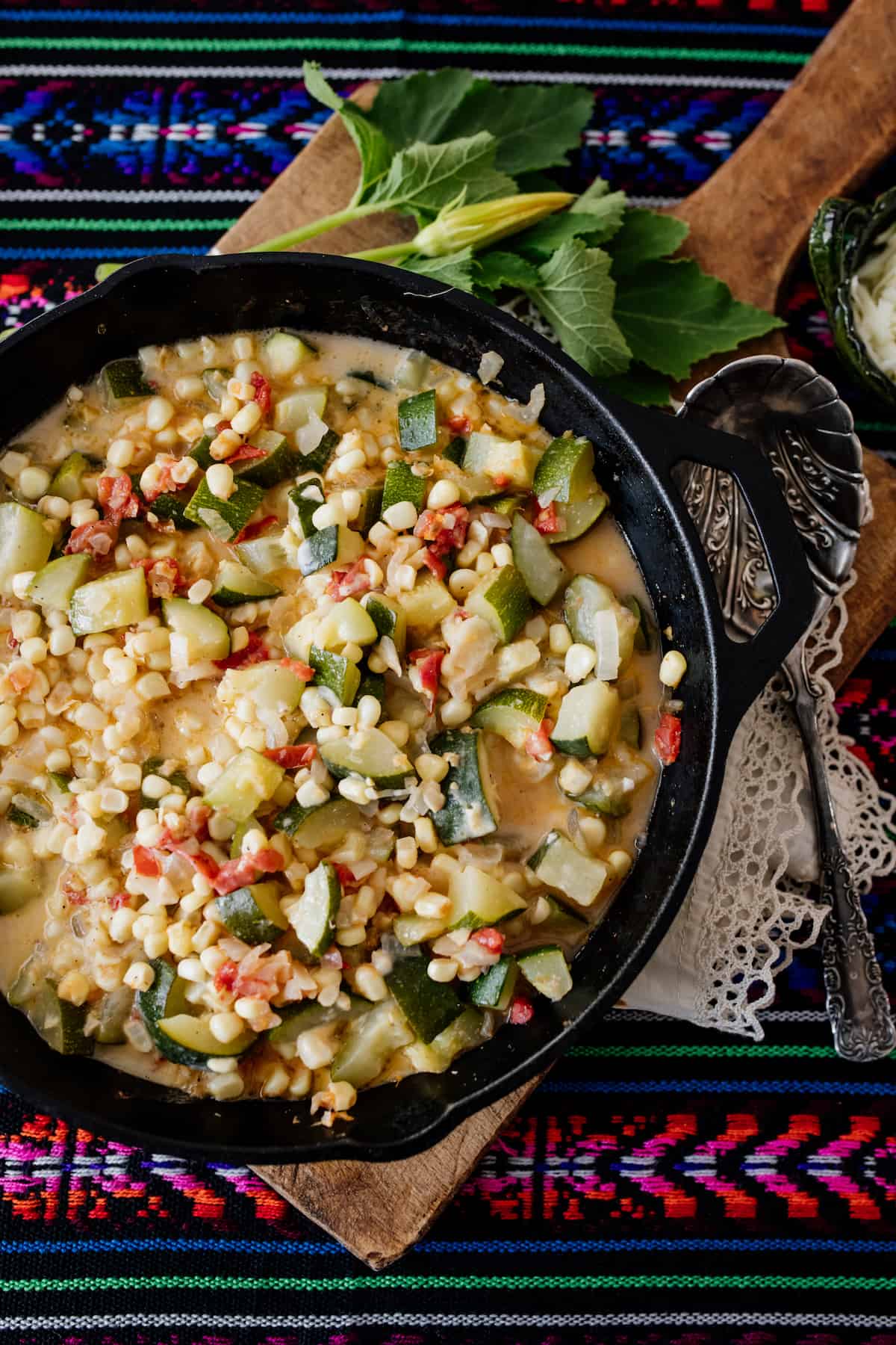 Calabacitas con Elote or Zucchini with Corn ready and served in an iron skillet on a colorful runner