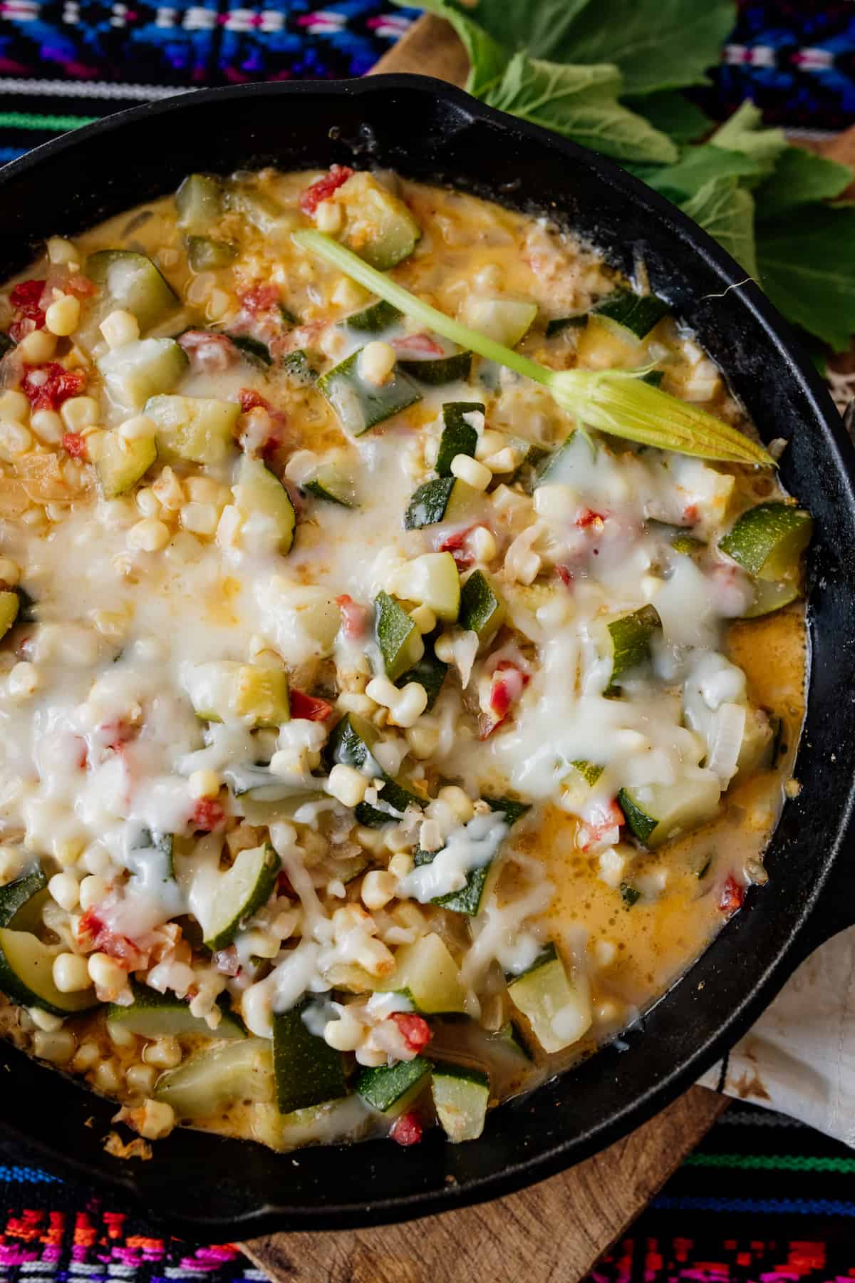 Closeup on the delicious Mexican Calabacitas con Elote or Zucchini with Corn topped with cheese in a cast iron skillet