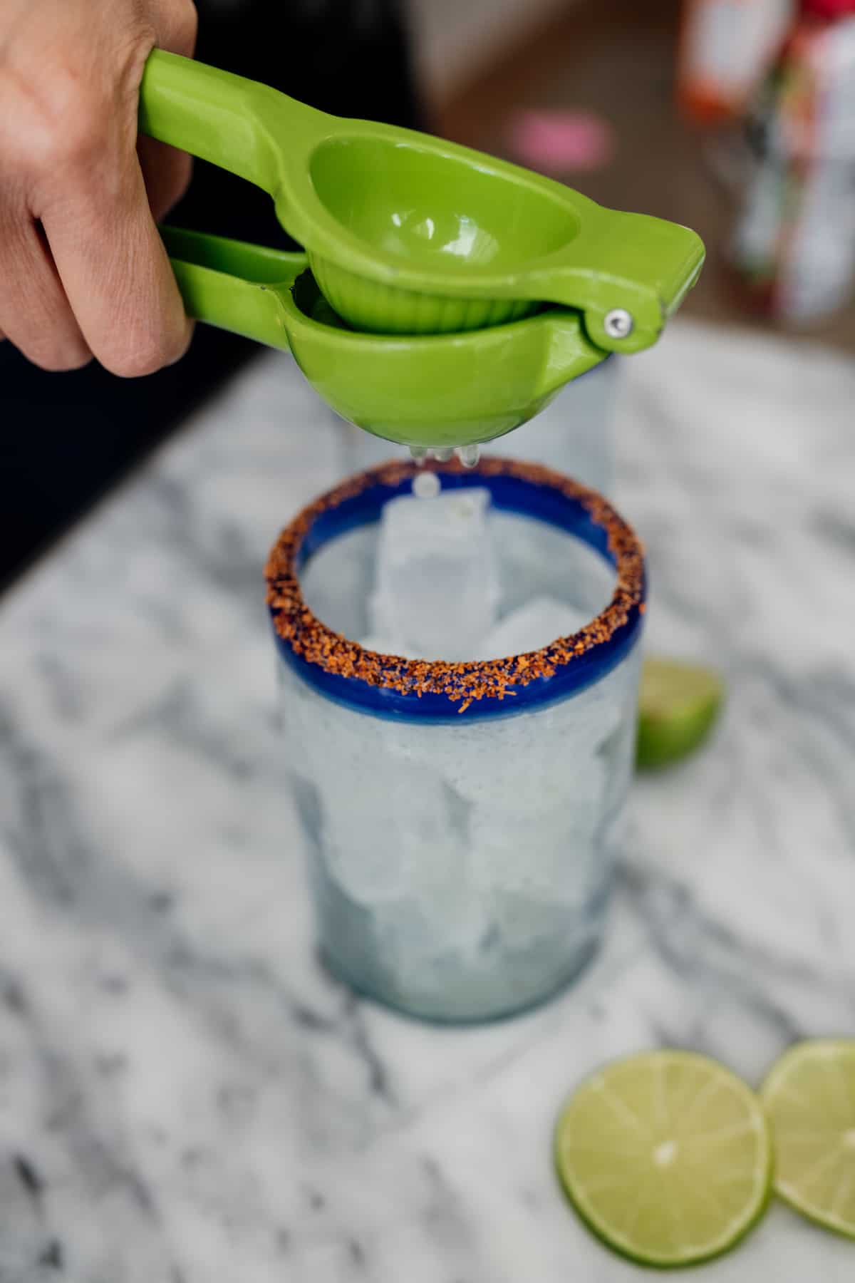 lime squeezer with fresh lime juice in a tajin rimmed glass with ice for a beer cocktail 