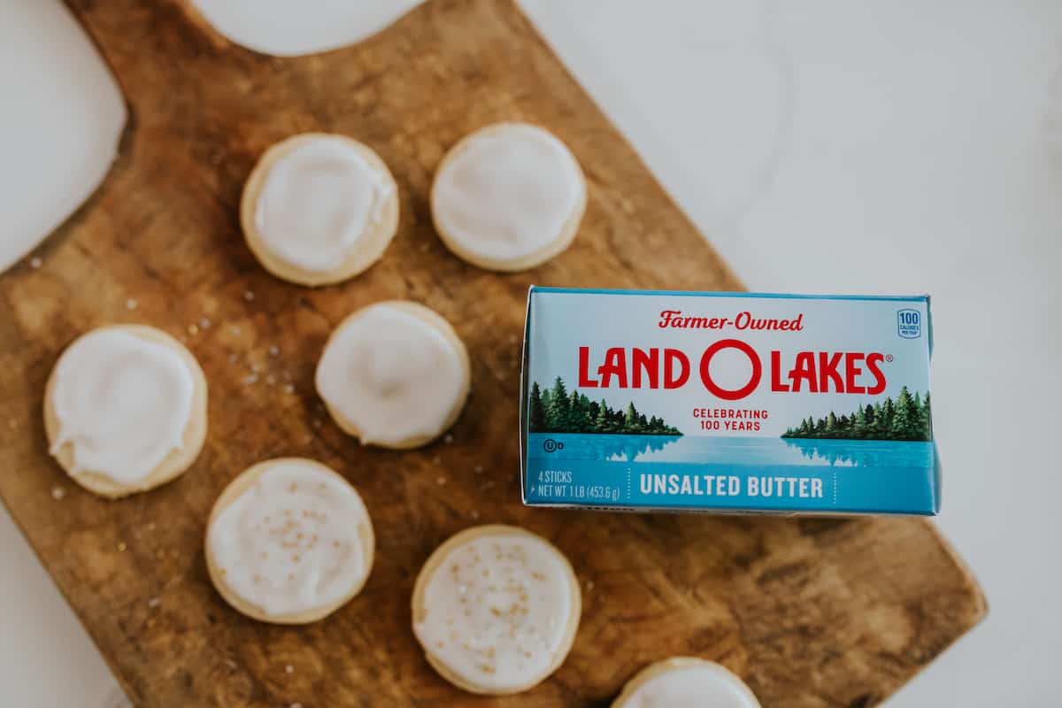 wooden board with glazed lemon sugar cookies next to a box of land o lakes unsalted butter