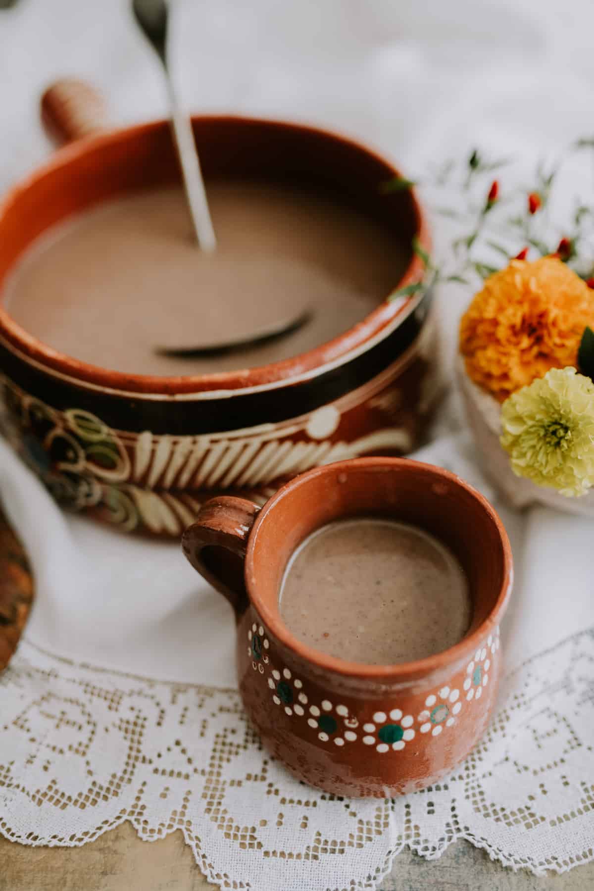 Mexican Hot Chocolate barro cazuela and cup with marigolds on the side