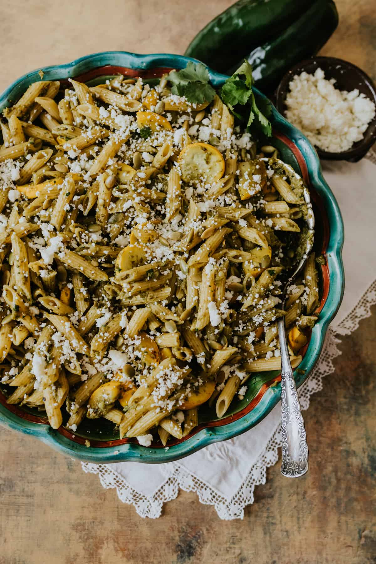 Spicy Cilantro Pesto Pasta topped with Cotija and pepitas in a larges called green bowl