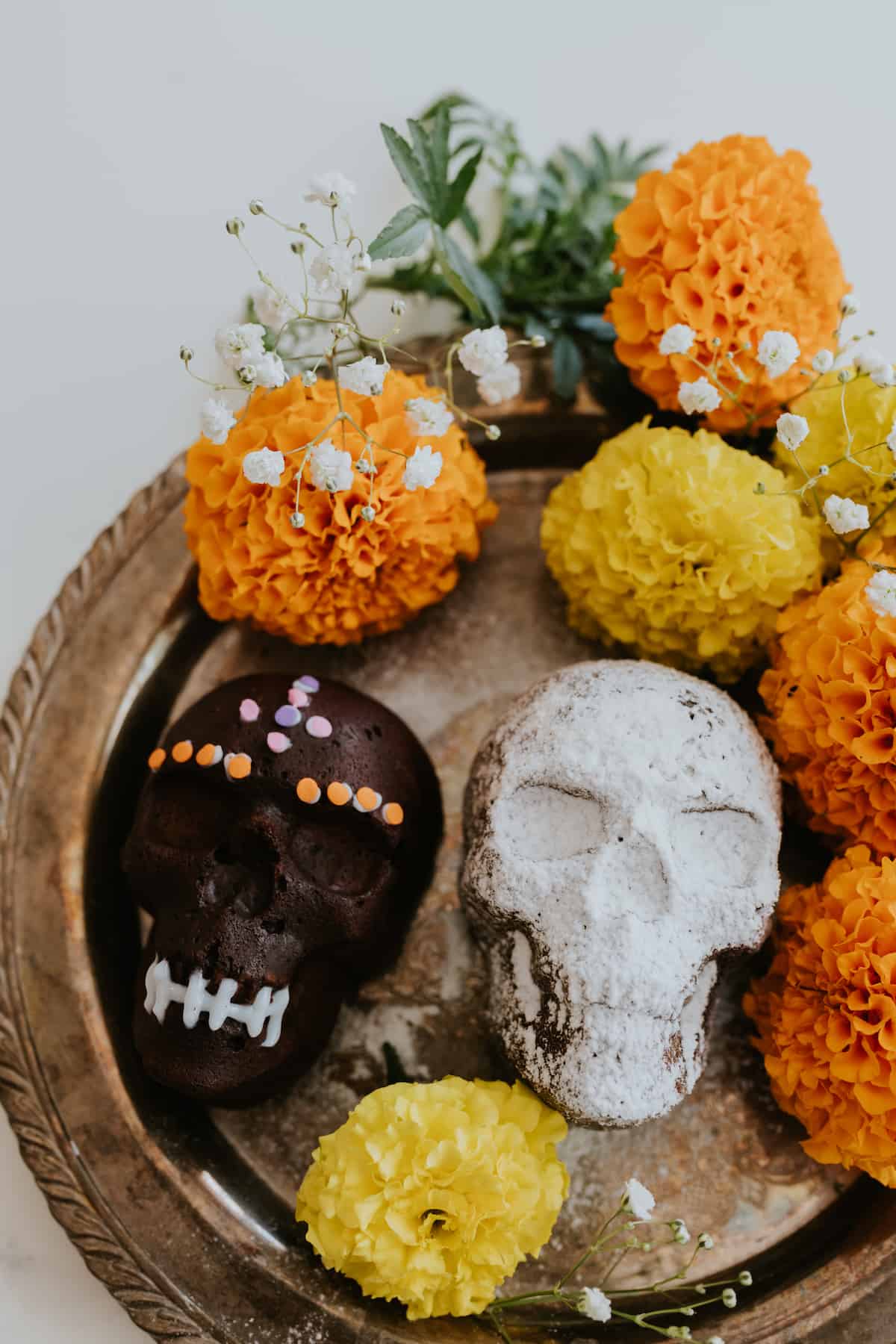 Chocolate Skull Cakes decorated for Dia de los Muertos surrounded by marigolds 