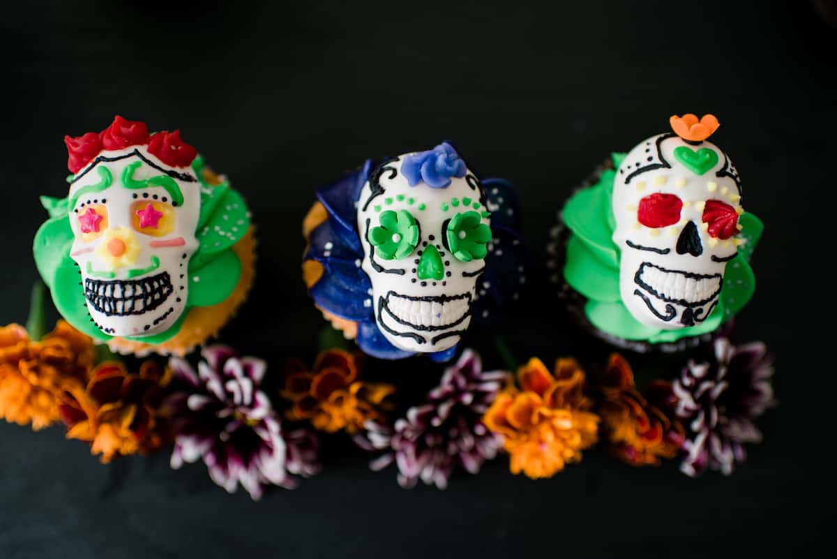 Overhead view of these festive DIY Dia de los Muertos candy skulls decorated with colorful frosting and served on op of a cupcake