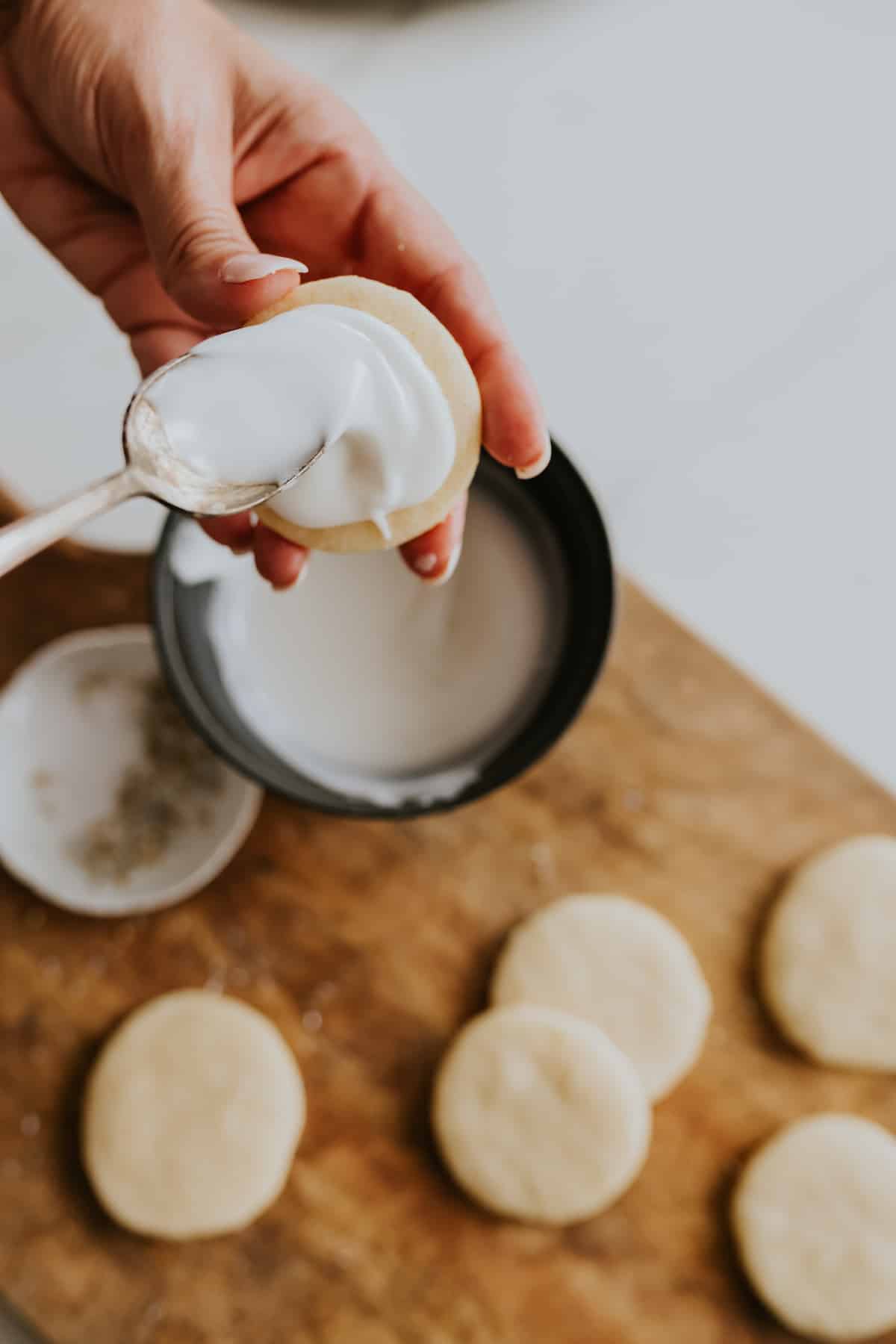 Hand adding lemon glaze to top of cookie using a spoon