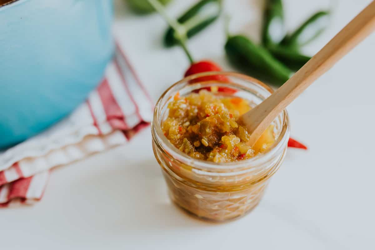 jalapeno jelly in a jelly jar with a wooden spoon