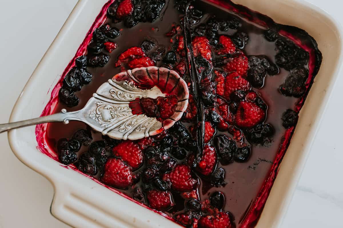 roasted berries in a baking dish with a vintage spoon