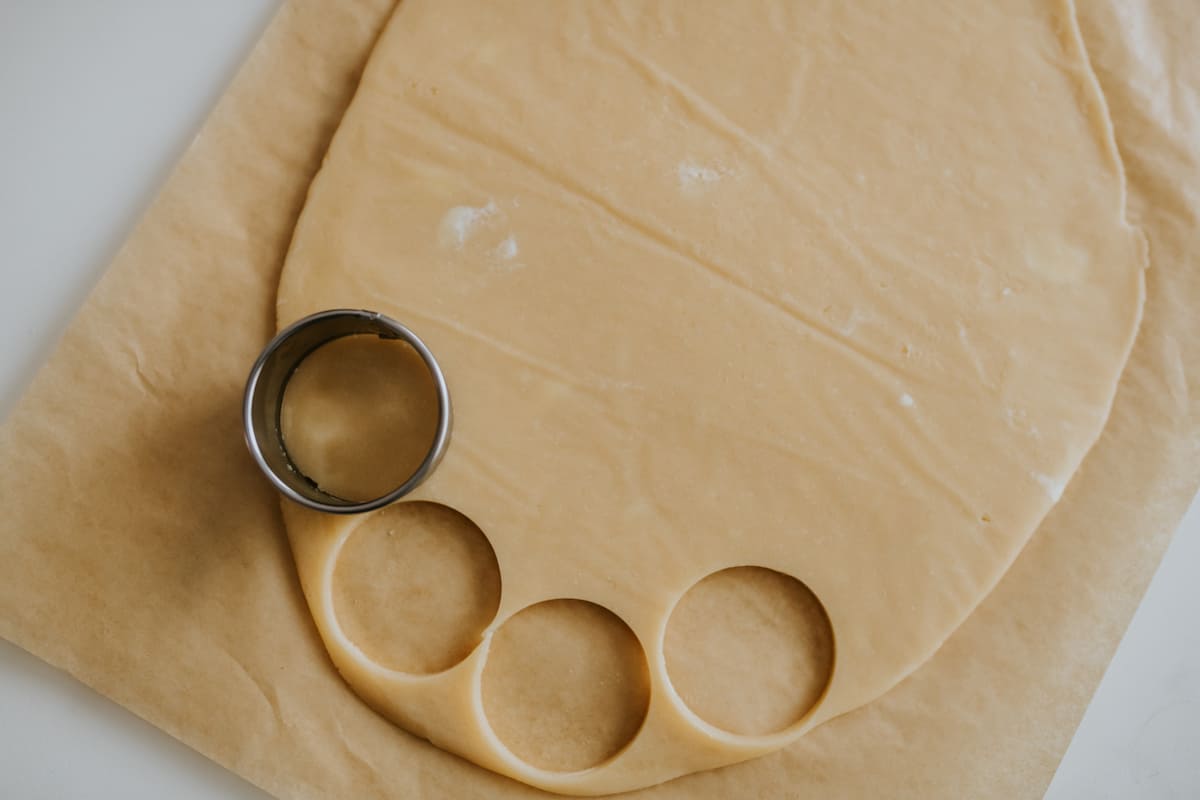 using a round cookie cutter to cut lemon cookie dough