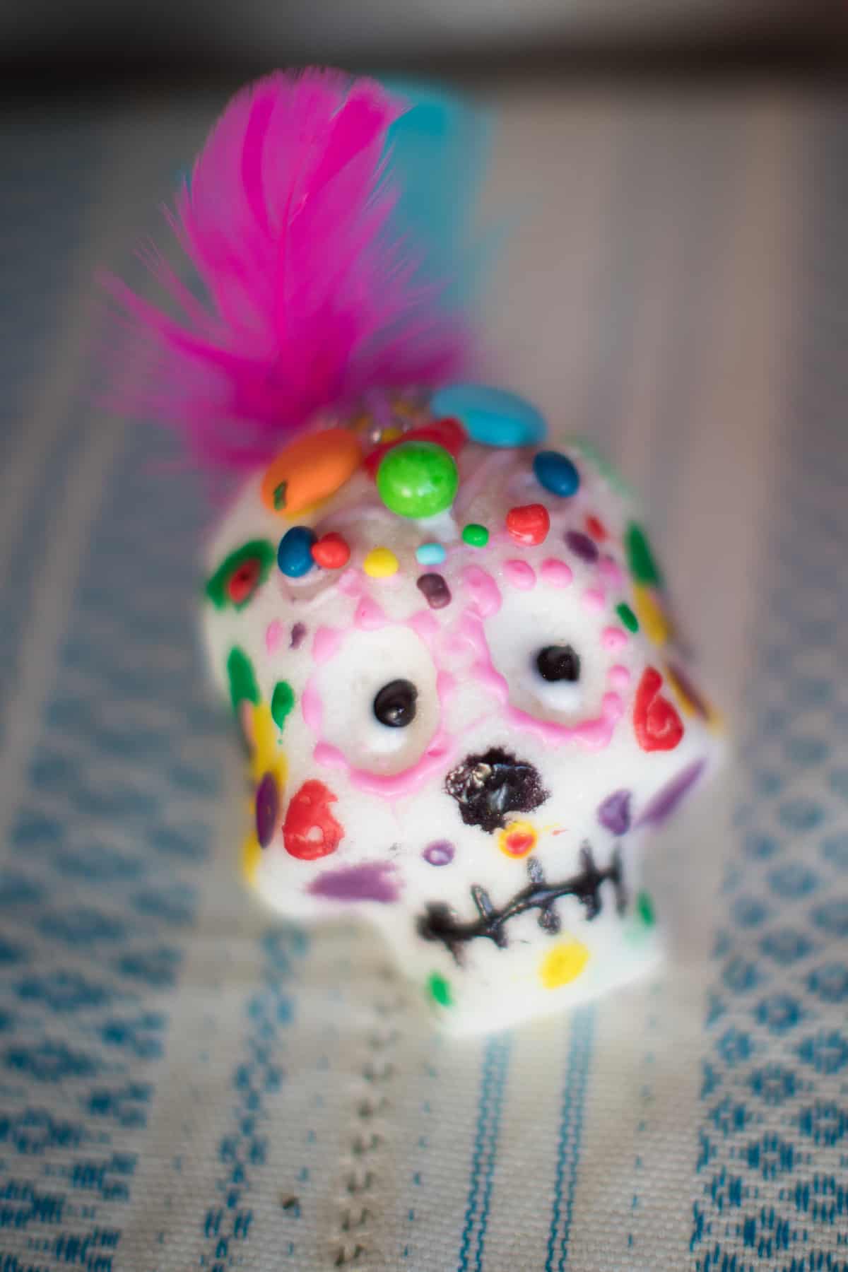 a colorfully decorated sugar skull for Dia de los Muertos with paint, feathers, and beads