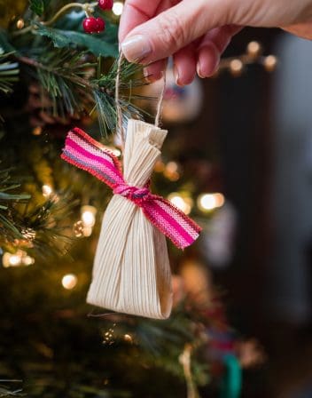 hanging a tamale shaped diy christmas ornament on the tree.