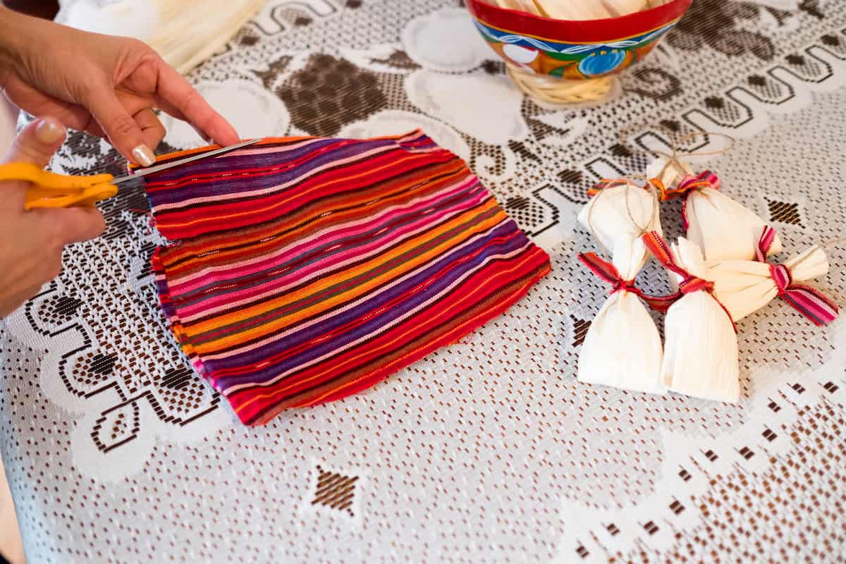 cutting strips of brightly colored fabric for making tamale shaped diy christmas ornaments.