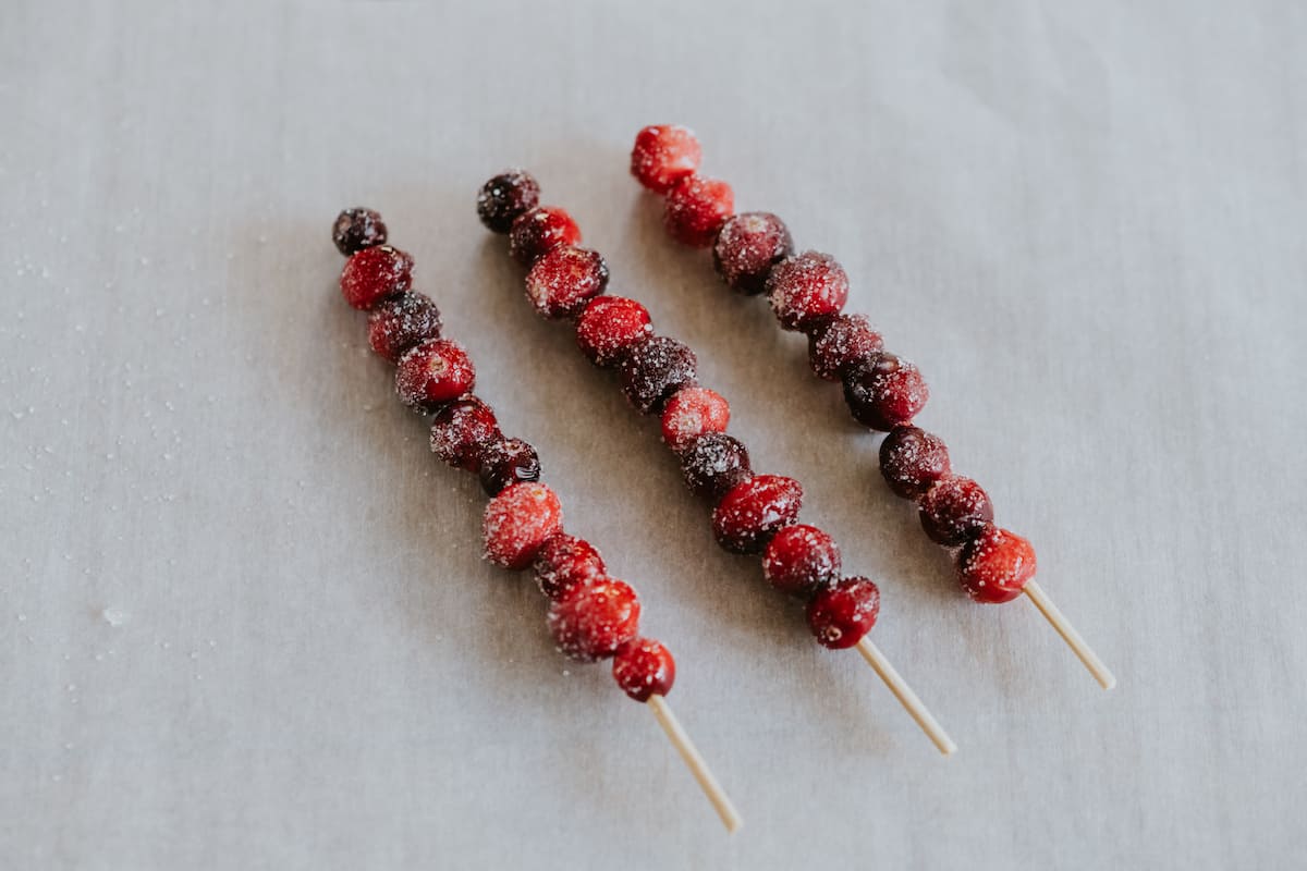 an overhead view of three sugared cranberry skewers to be used as a garnish for these cranberry margarita Christmas cocktails