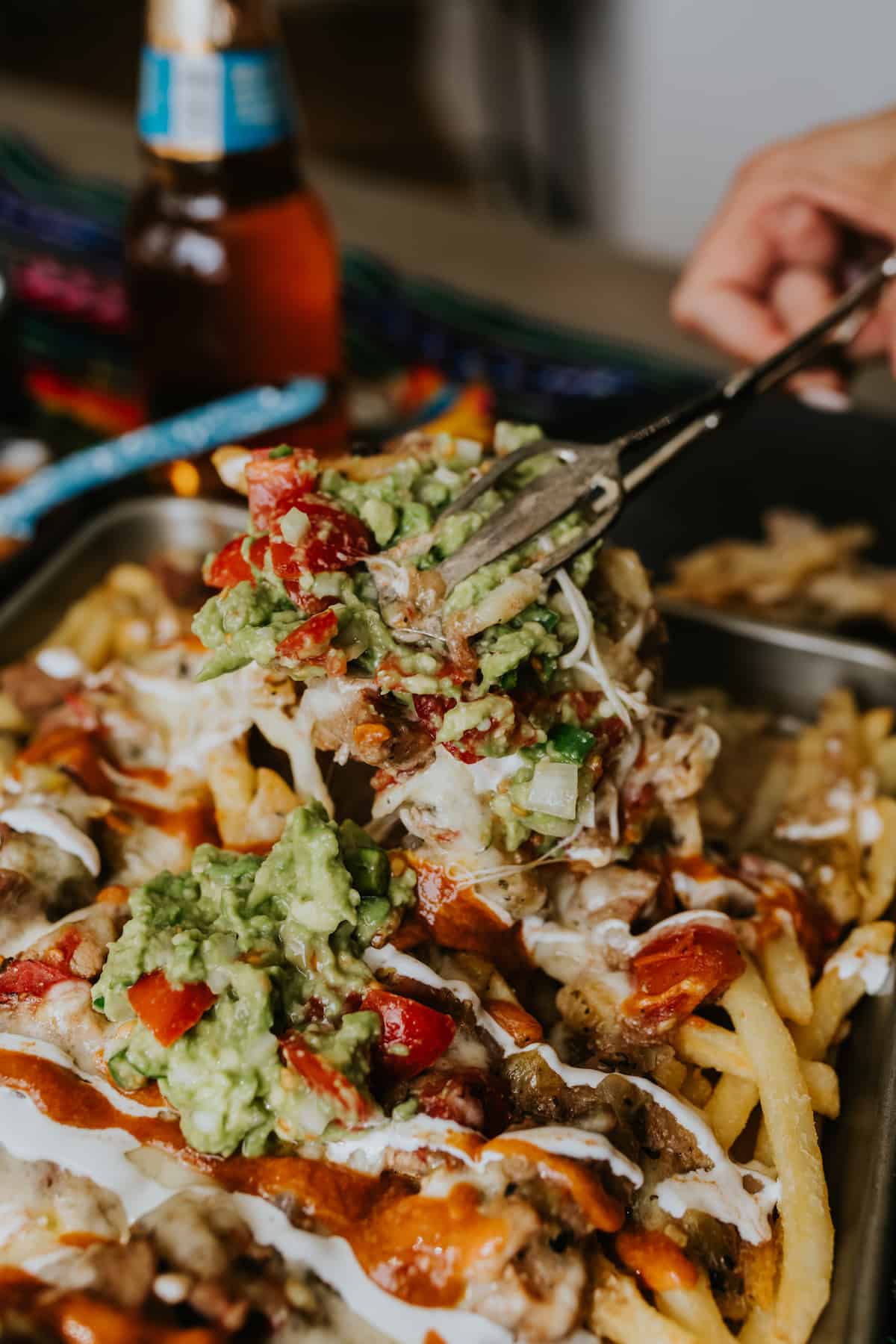Pork Green Chile Loaded Nacho Fries being served with tongs