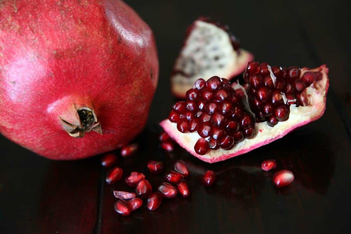 whole pomegranate behind a broken open fruit revealing the beautiful arils.