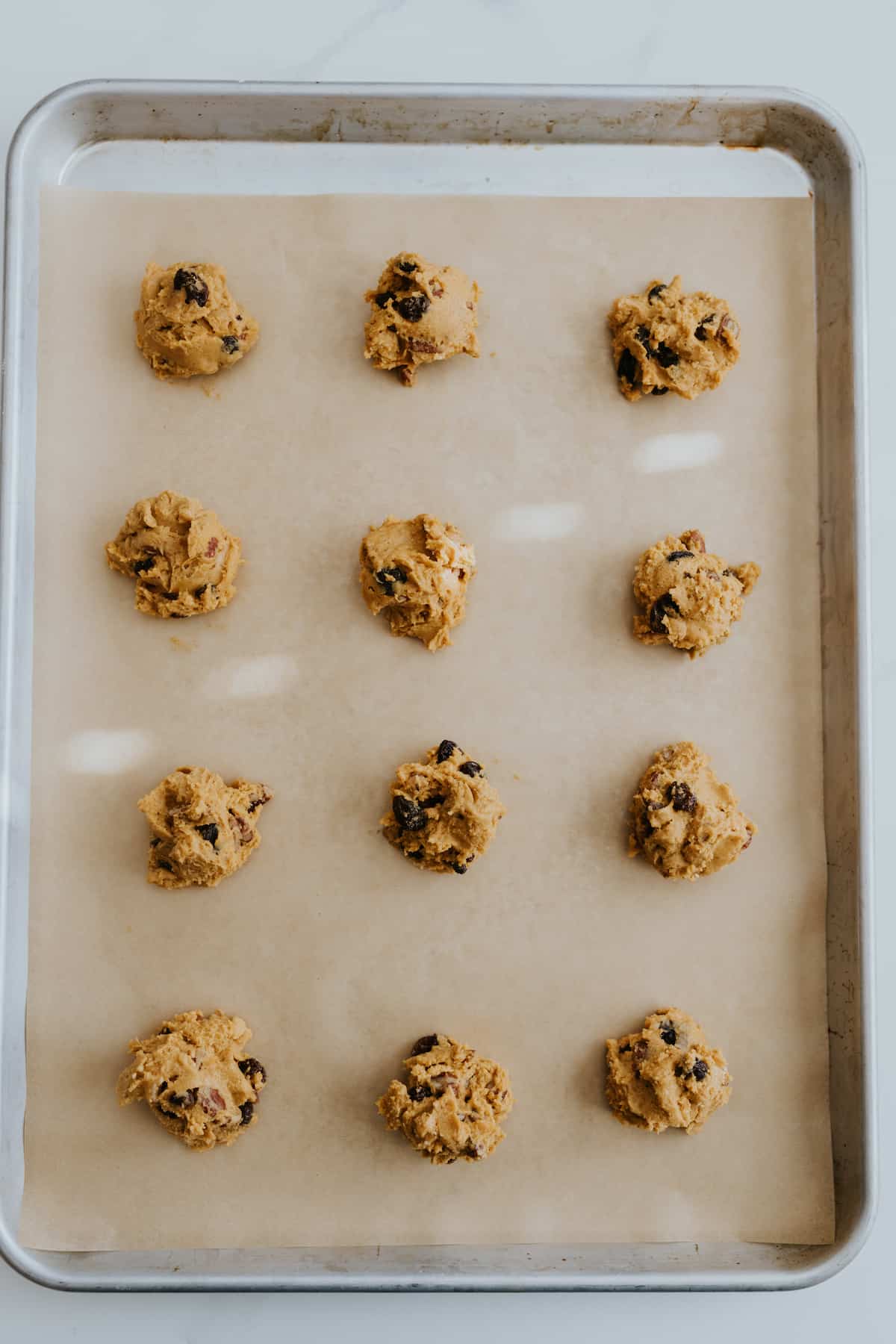 dropped tablespoons of pumpkin spice cookie dough on a parchment lined cookie tray.