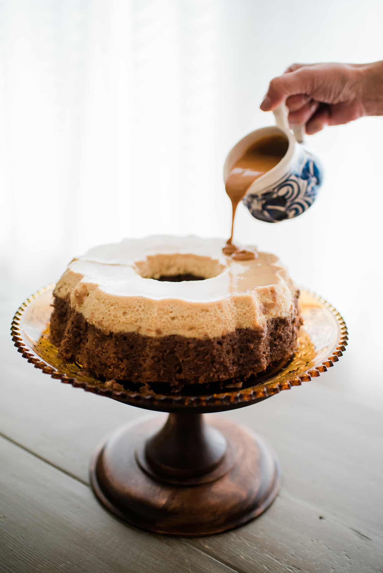 A hand pouring dulce de leche over a homemade chocoflan aka impossible cake.