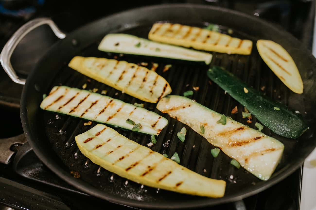 thin slices of summer squash and zucchini roasting in a grill pan.
