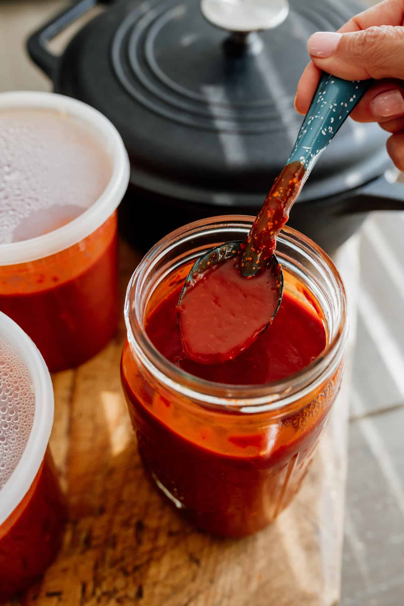 spoon in a mason jar of homemade red chile sauce.