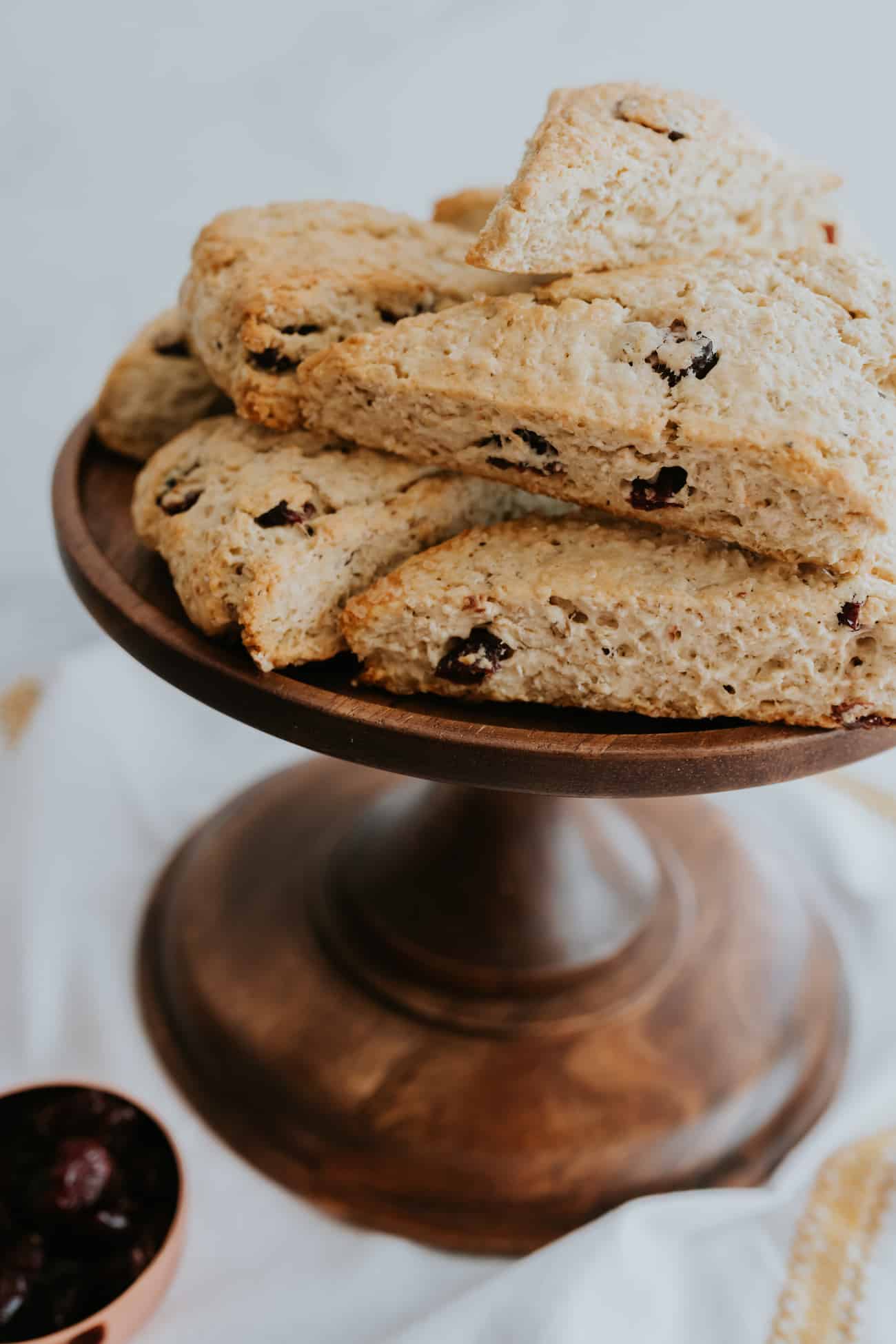 Cranberry Maple Oatmeal Scones stacked on a wooden cake pedestal.