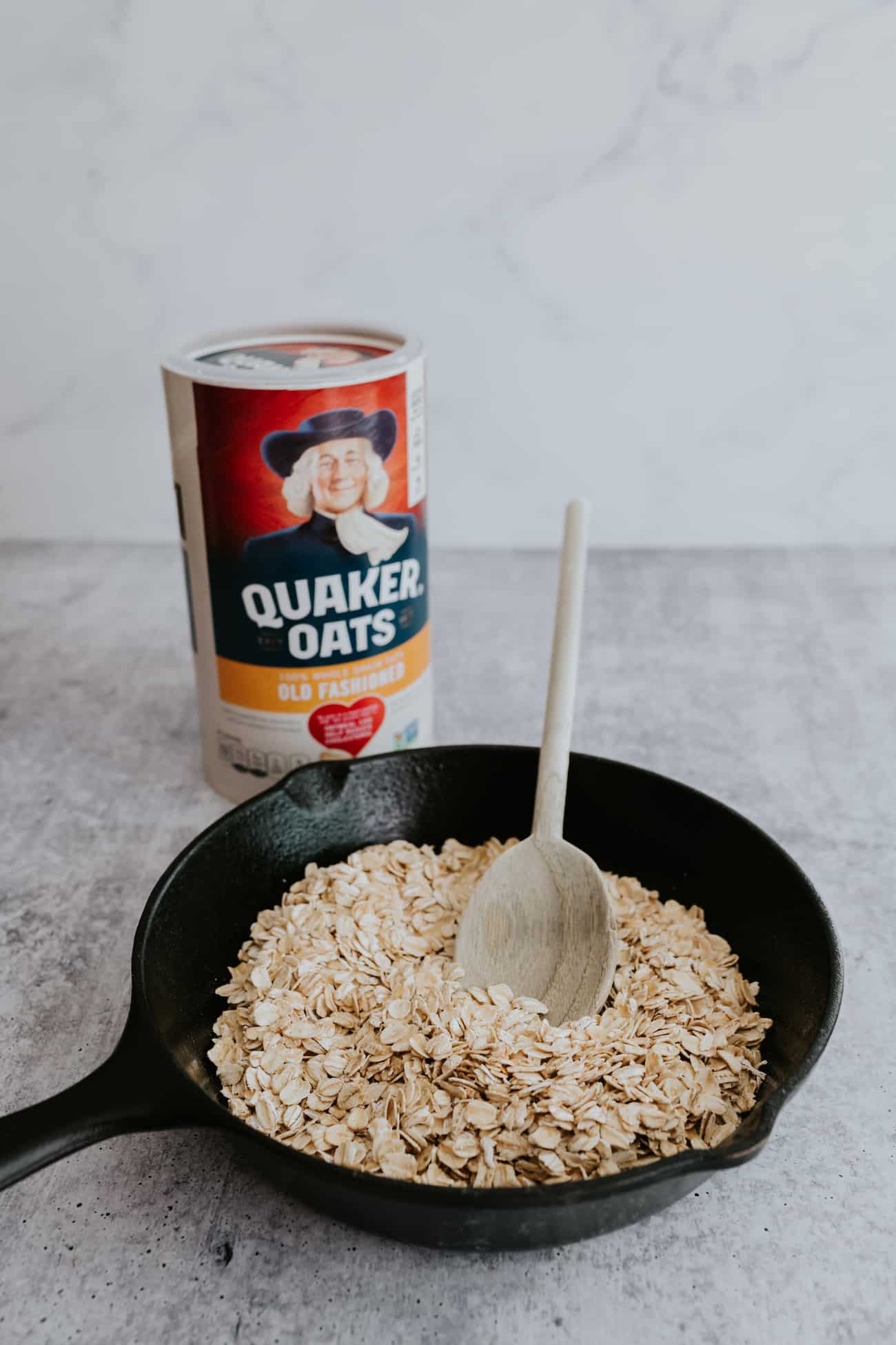 rolled oats in a dry cast iron pan with a wooden spoon for toasting.