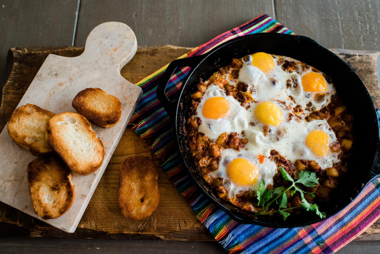 huevos rancheros in a cast iron skillet with toast on the side. 