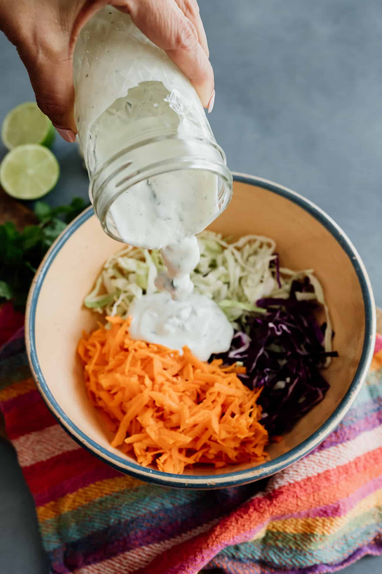 spicy coleslaw dressing being poured over grated veggies.