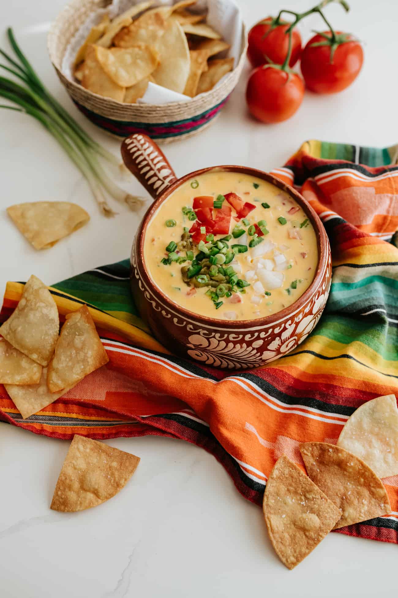tex-mexchile con queso  in a handled bowl with a side of tortilla chips.