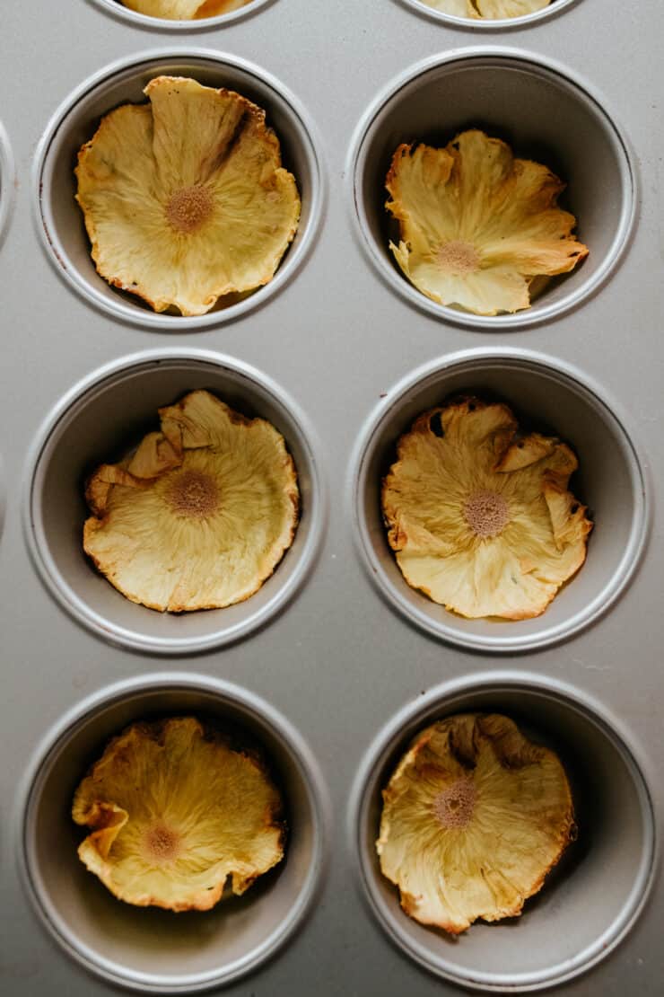 Dried pineapple flowers cooling in a muffin tin to form dried pineapple flowers.