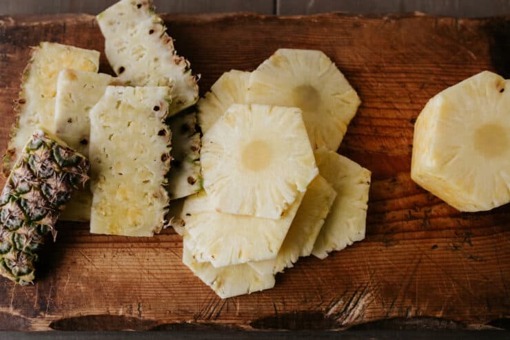 slices of fresh pineapple on a wooden cutting board.