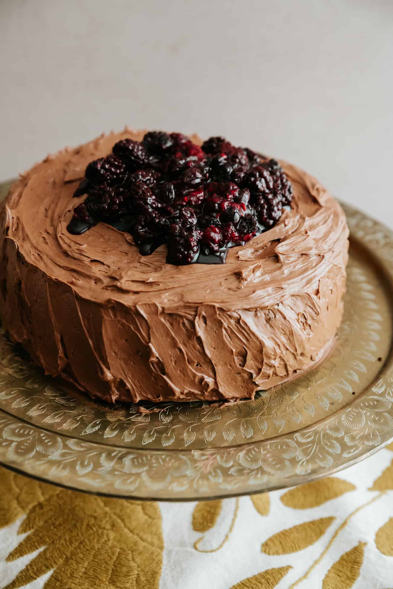 whole double layered chocolate cake with mocha buttercream and topped with roasted berries.