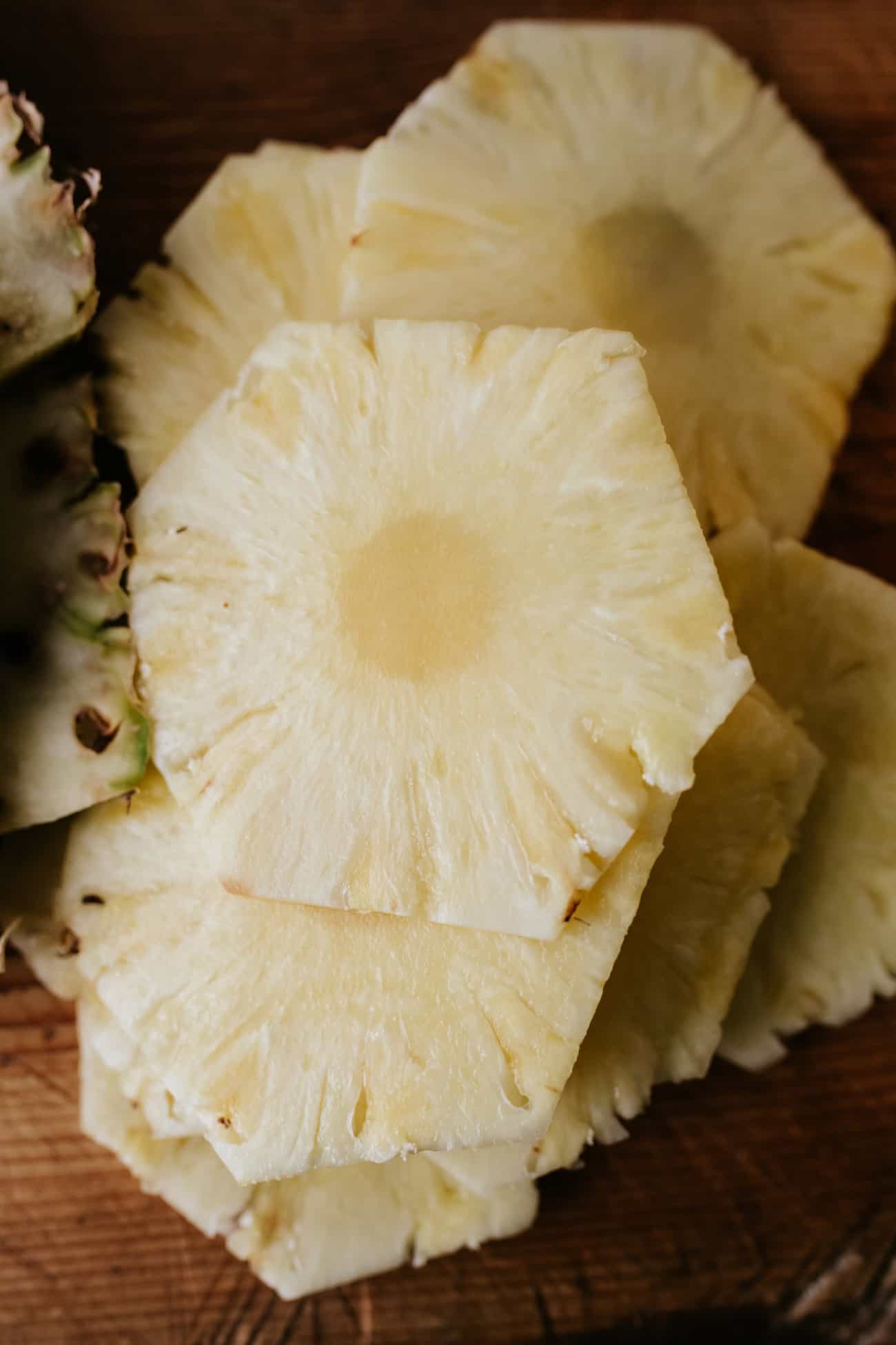 Close up of fresh pineapple slices on a wooden board.