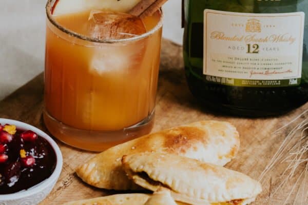 sparkling whisky apple cider with sweet empanadas and a bottle of buchanans whisky.