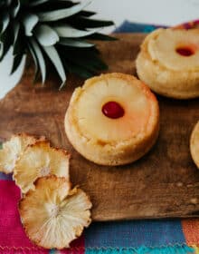 mini pineapple upside down cake on a wooden cutting board with pineapple flowers and a pineapple crown.