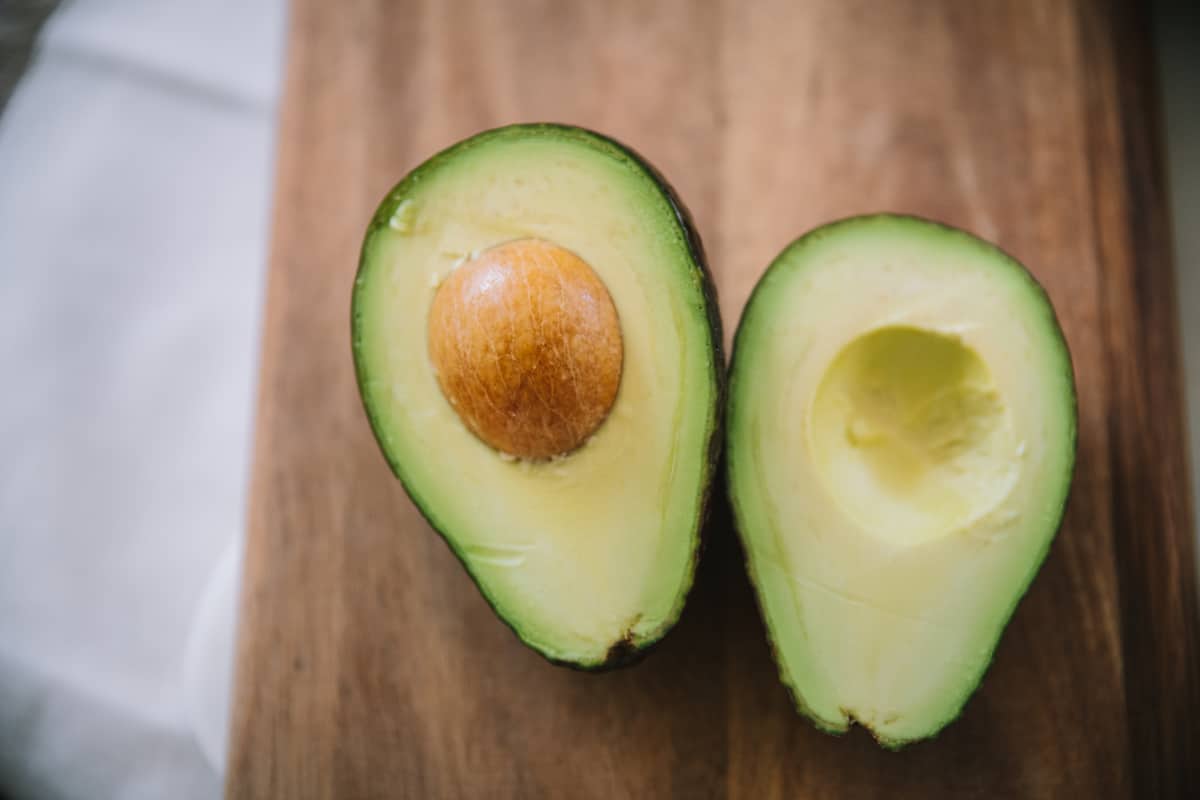 halved avocado on a wooden cutting board.