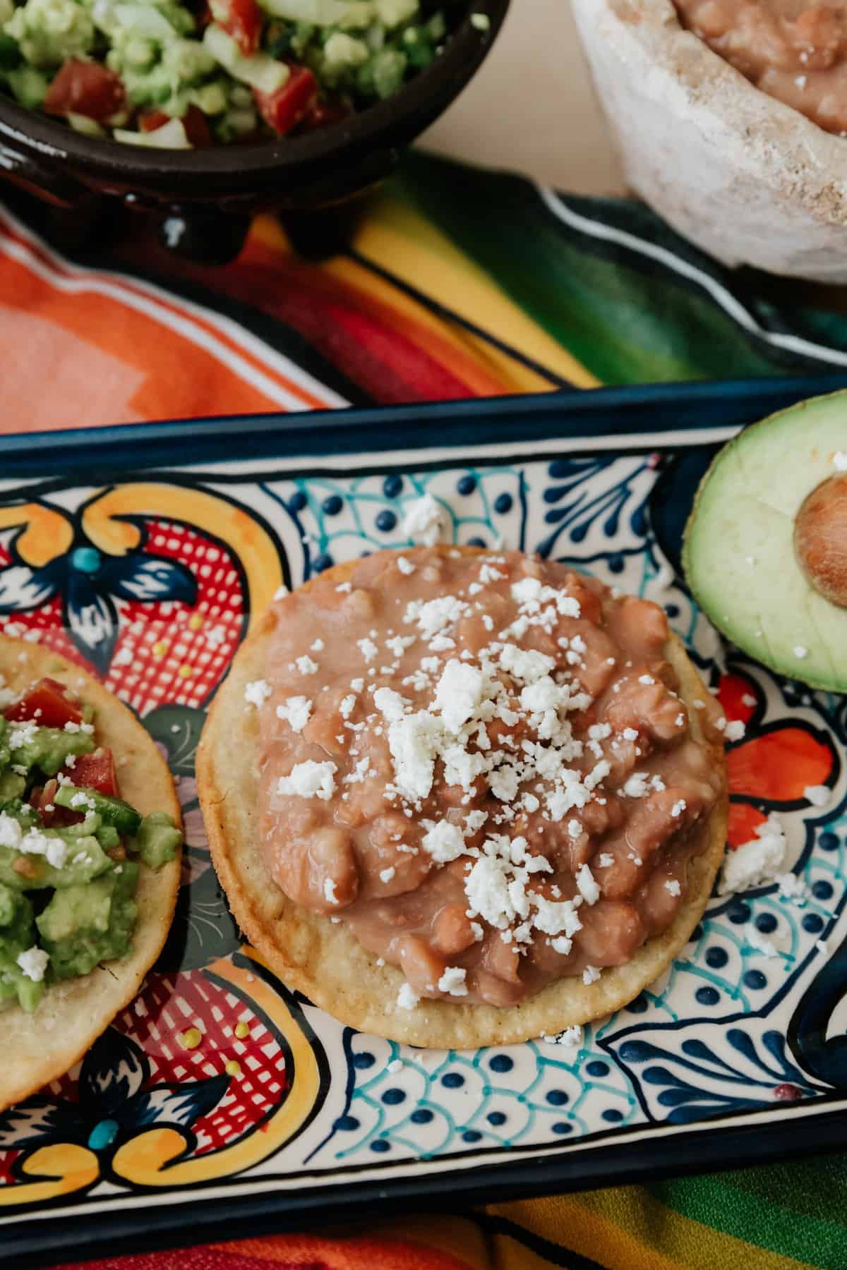 Refried bean tostada with queso fresco on a talavera platter.
