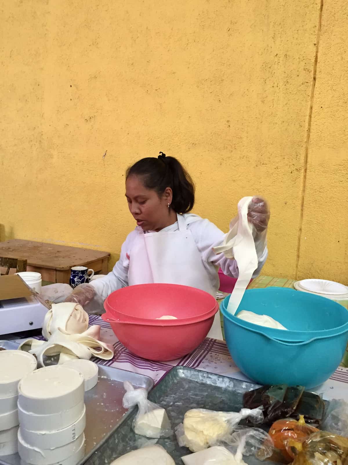 Mexican woman pulling and stretching ribbons of queso oaxaca.