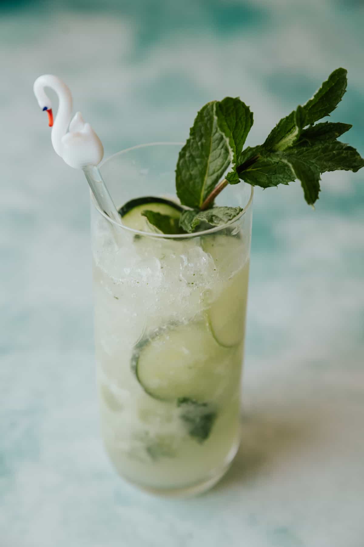 collins glass filled with cucumber mint mojito on a bluish table. 