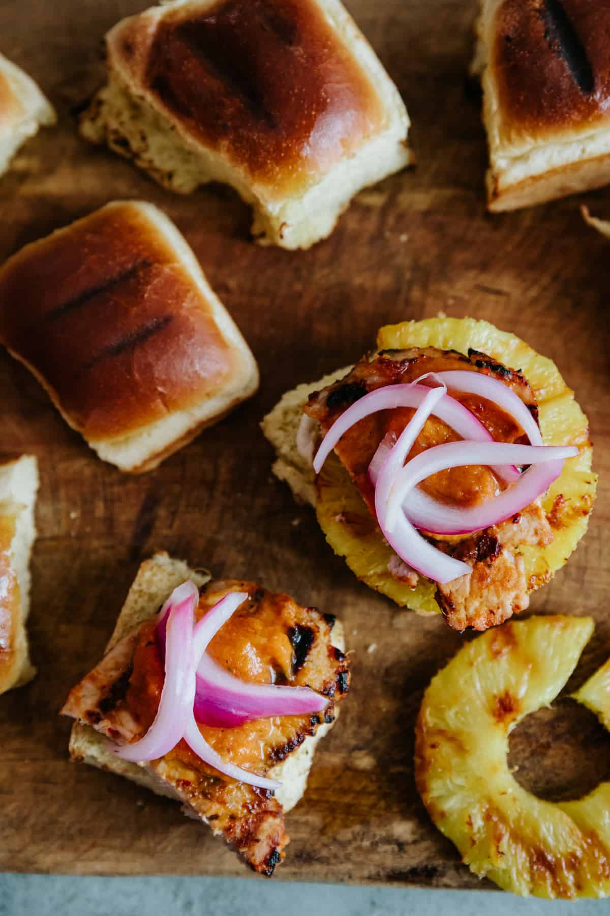 overhead closeup of mexican pork chop slider with pickled onions and grilled pineapple. 