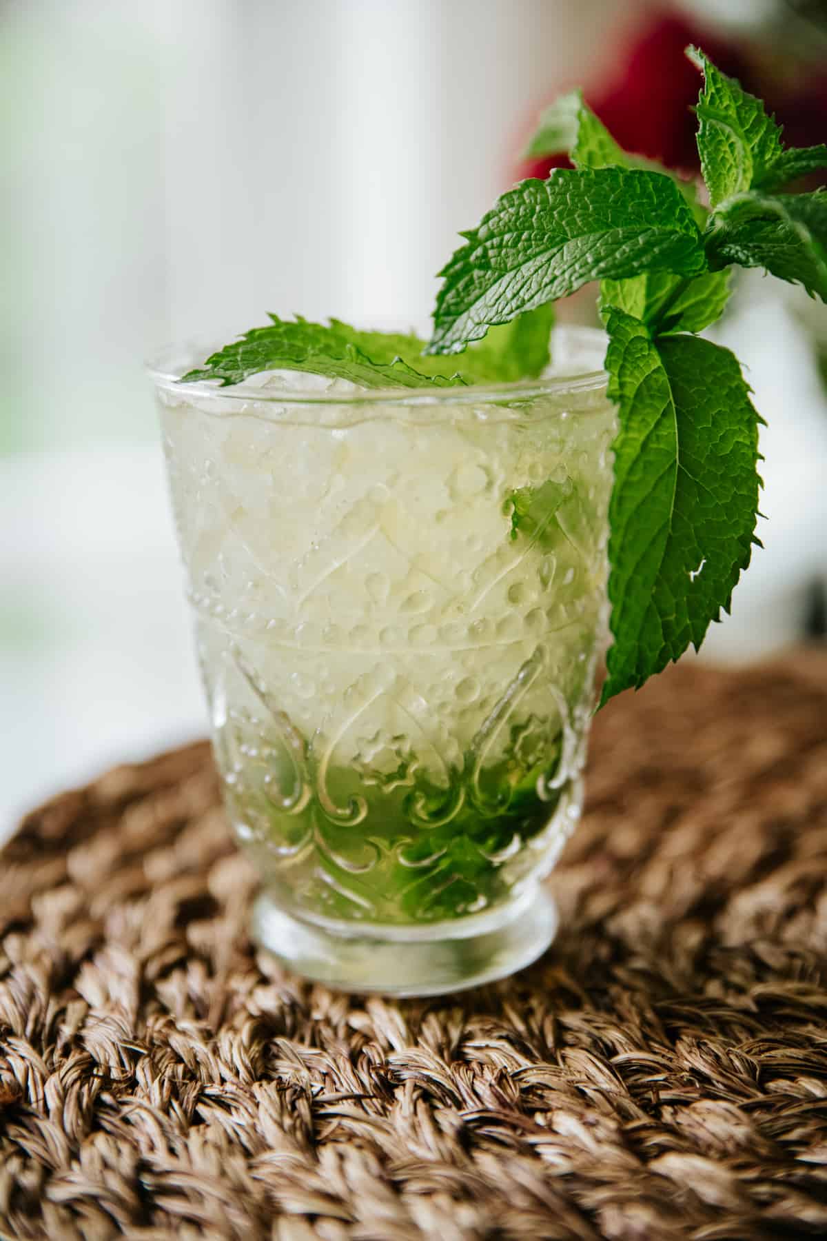 classic mint julep in a clear etched glass cup with a large sprig of mint as garnish. 