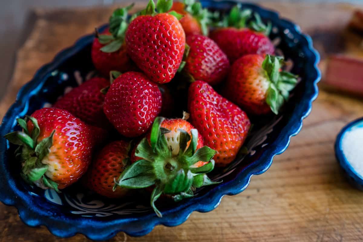 fresh strawberries in a blue fluted edge bowl. 