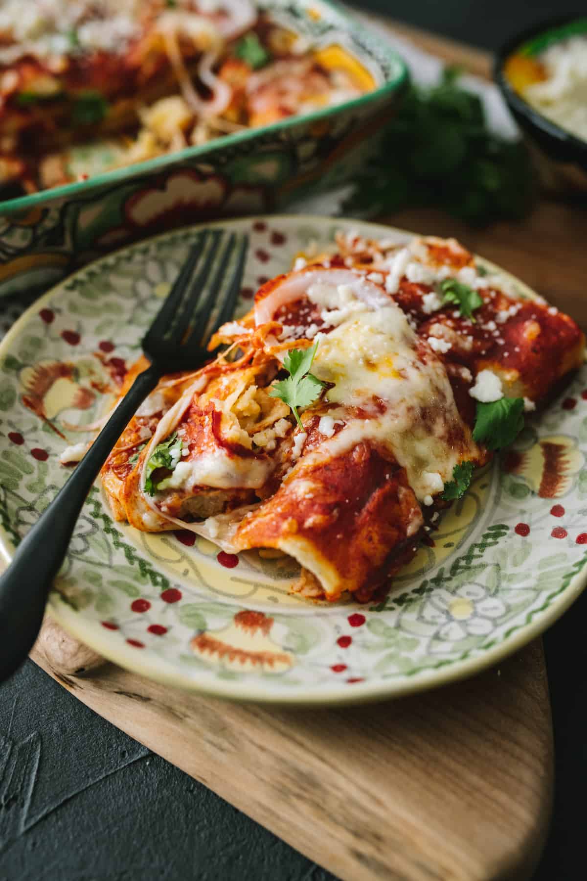 red Black Bean & Rice Enchiladas rolled served on a Mexican talavera plate with a black fork.