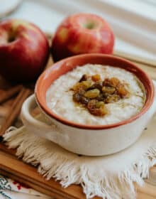 white and terracotta bowl with handles filled with mexican oatmeal and topped with a cinnamon apple raisin compote.