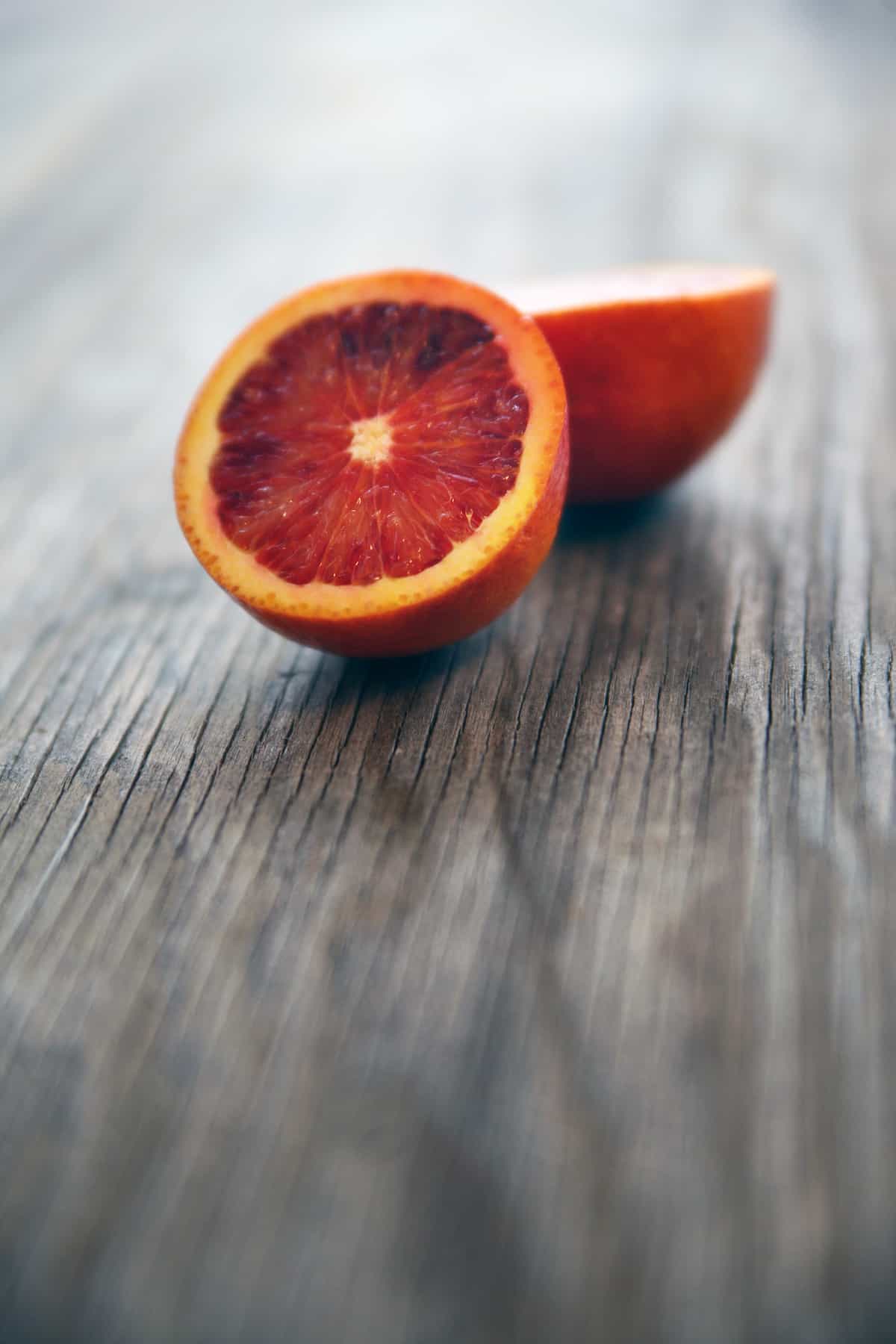 naranja sanguina a la mitad sobre una mesa de madera.