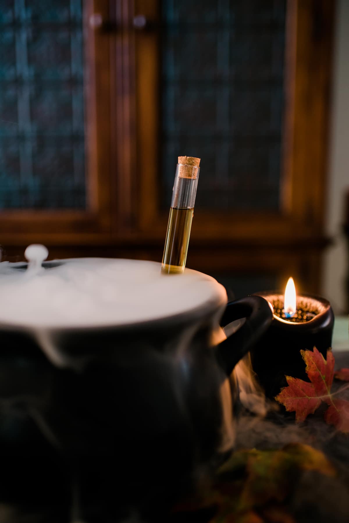 caldero de sangría de halloween de brebaje de bruja empañando con hielo seco junto a una vela negra encendida. 