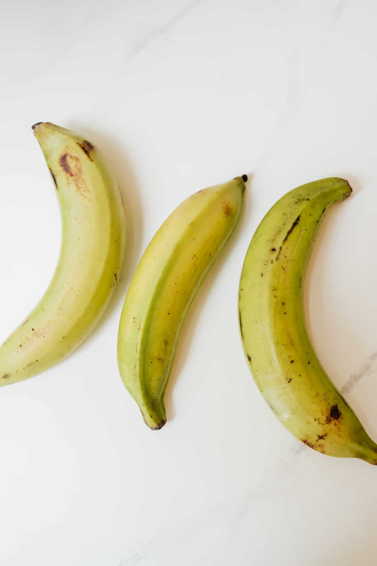 3 green plantains on a white table
