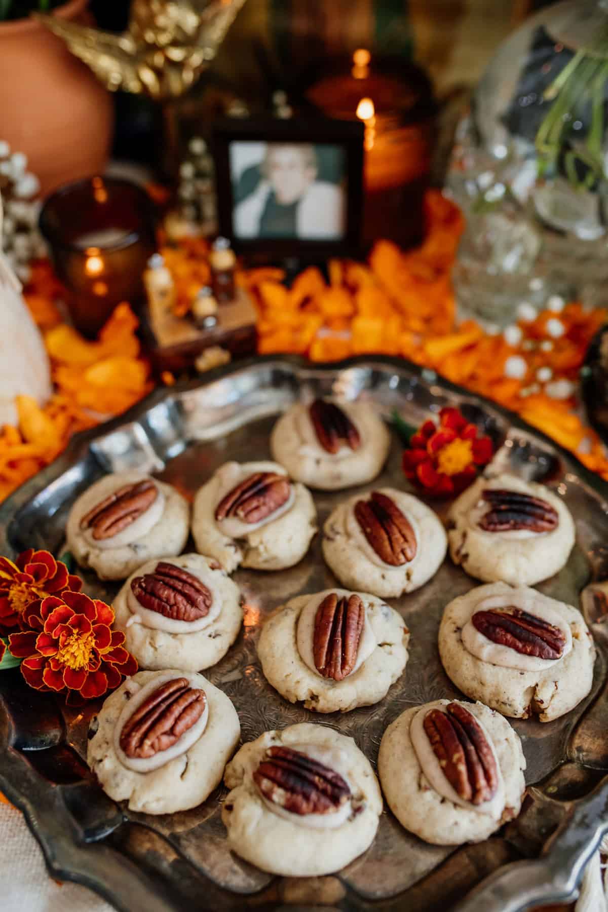 Double Pecan Thumbprint cookies on a silver platter with marigolds on day of the dead altar.