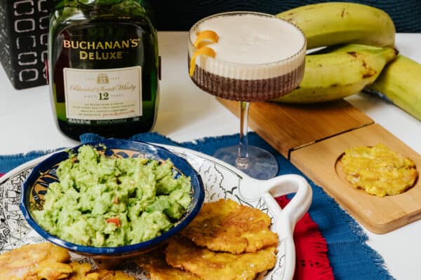 platter of tostones with guacamole and a stemmed glass with a whisky and coffee cocktail.